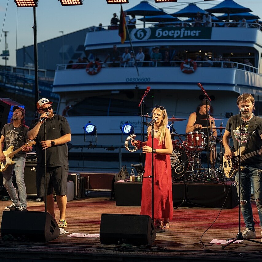 Abendauftritt auf der Seebühne beim HafenKulturFest am Karlsruher Rheinhafen, mit dem Fahrgastschiff MS Karlsruhe im Hintergrund.