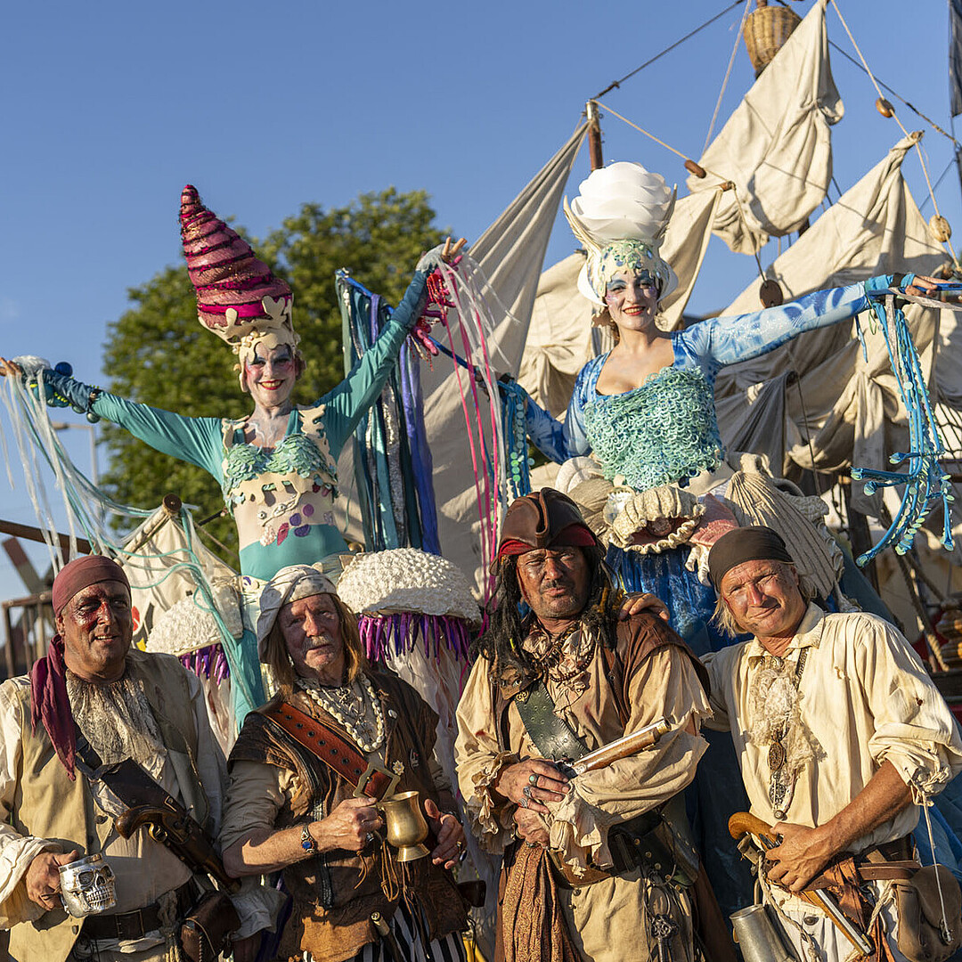 Kölner Piraten und Stelzenläuferinnen als Walking Act beim HafenKulturFest am Karlsruher Rheinhafen, in fantasievollen Kostümen vor maritimer Kulisse.