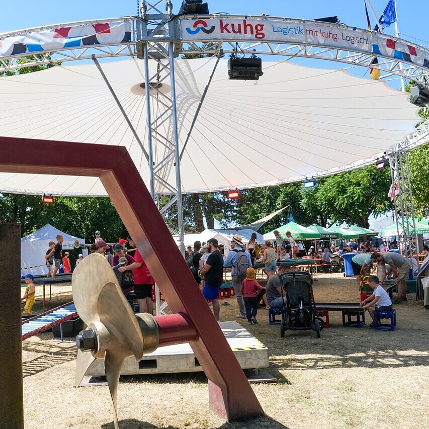 Überdachte Aufenthaltsfläche mit dem Magic Sky beim HafenKulturFest am Karlsruher Rheinhafen, die Besucherinnen und Besuchern Schutz und Schatten bei warmem Wetter bietet.