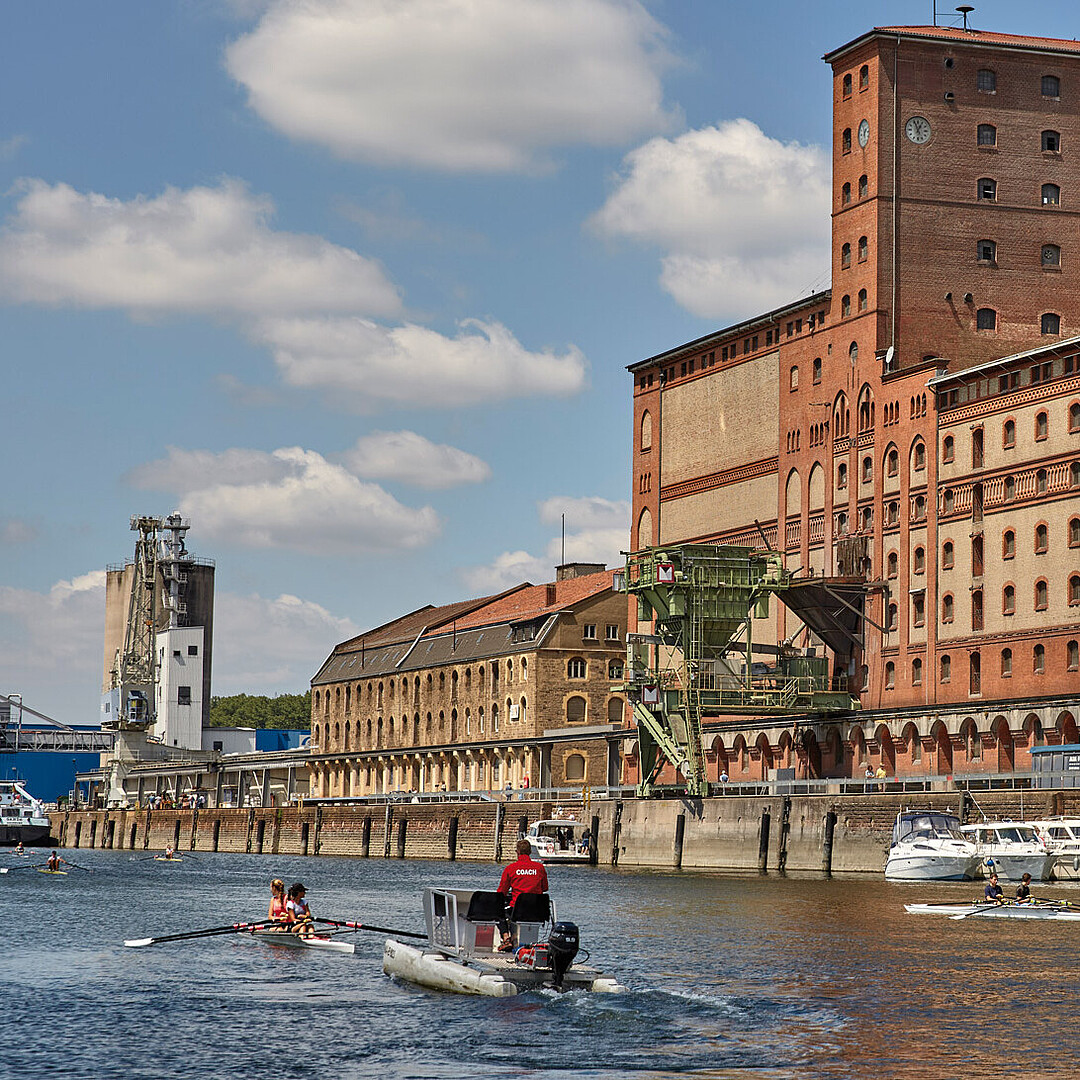 Hafenbecken 2 im Rheinhafen Karlsruhe mit historischen Hafenbauten, genutzt sowohl für den Hafenbetrieb als auch von Wassersportlern wie den Rheinbrüdern.