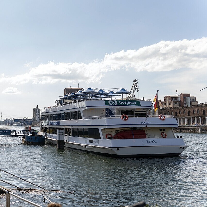 Fahrgastschiff MS Karlsruhe am Anleger im Rheinhafen Karlsruhe bei Tageslicht, mit Gästen an Bord.
