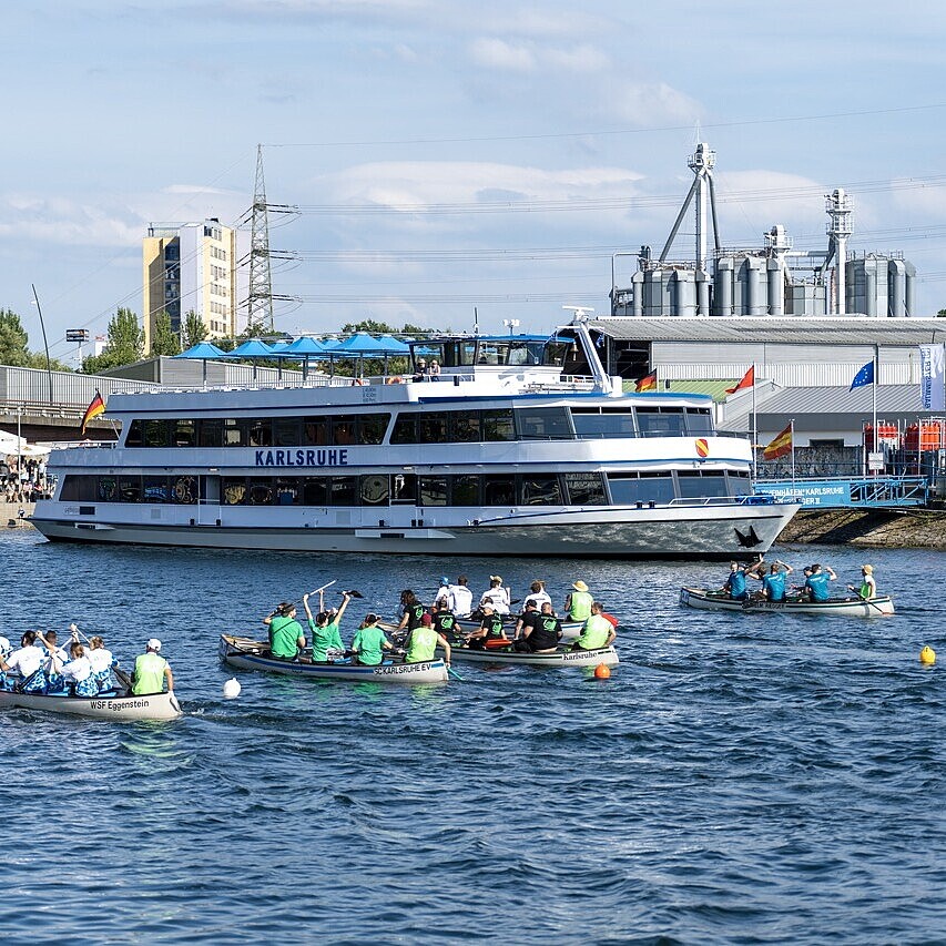 Fahrgastschiff MS Karlsruhe beim HafenKulturFest im Rheinhafen Karlsruhe, mit Teilnehmenden der Hafenregatta in Ruderbooten auf dem Wasser.