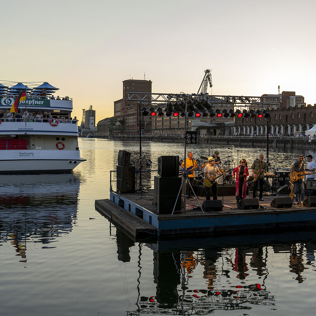 Abendauftritt auf der Seebühne beim HafenKulturFest am Karlsruher Rheinhafen, mit dem Fahrgastschiff MS Karlsruhe im Hintergrund.